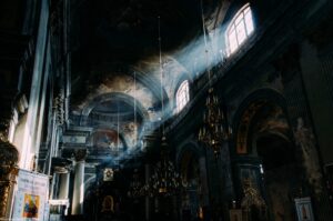 Light pouring through a church window into a dark nave