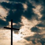 Cross silhouetted against a dramatic cloudy sky