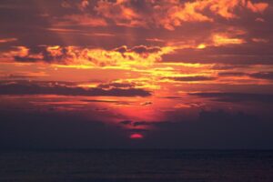 Fiery orange sunset clouds over dark water