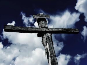 Wooden cross against a deep blue sky with clouds