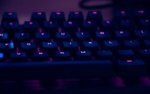 Backlit keyboard glowing purple and blue in the dark