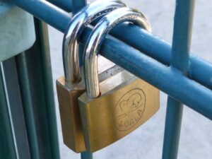 Brass padlock on a blue metal fence