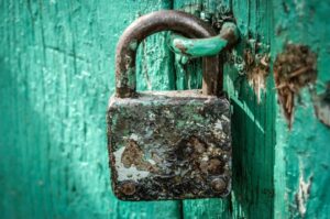 Rusty padlock on a weathered teal door